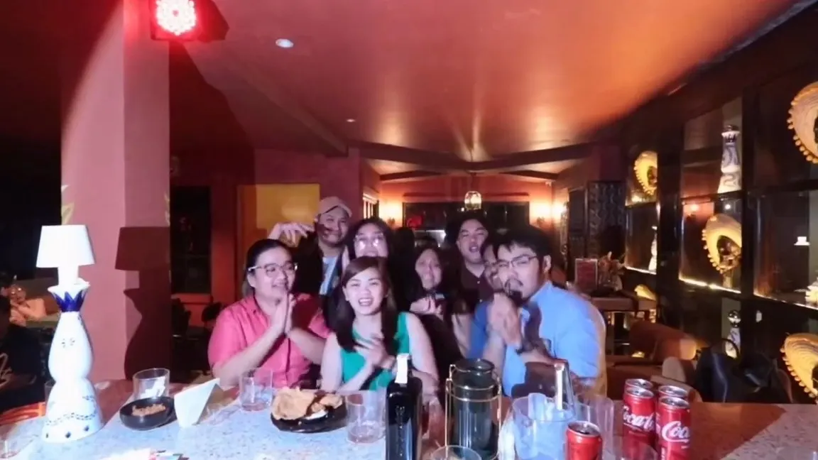 Guests raising their glasses around a long table at a birthday dinner
