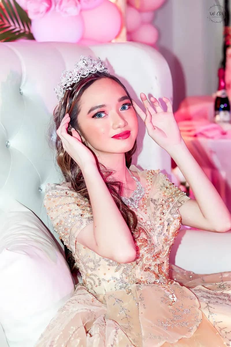 Debutante touching her hair while seated in a sparkling gown
