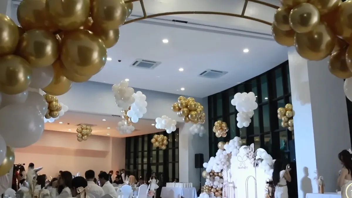 Function room decorated with gold and white balloon clusters for an anniversary celebration