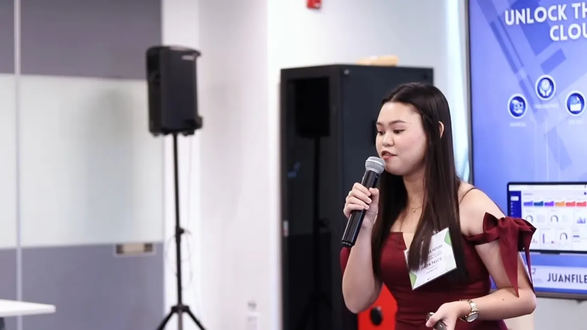 Host in a red dress speaking into a microphone at a corporate conference